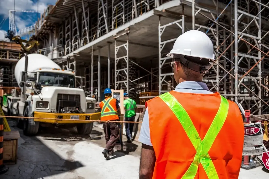 Site engineer in high-visibility vest supervising work beside a concrete truck